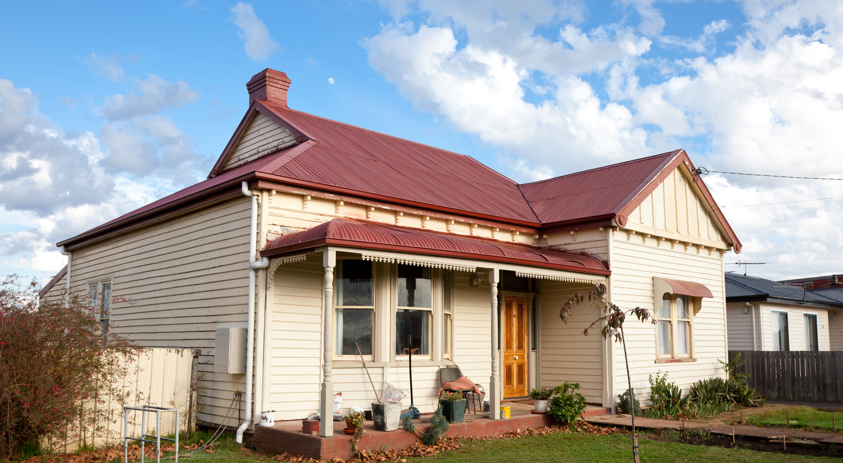 An old house with a red roof and grass front yard.