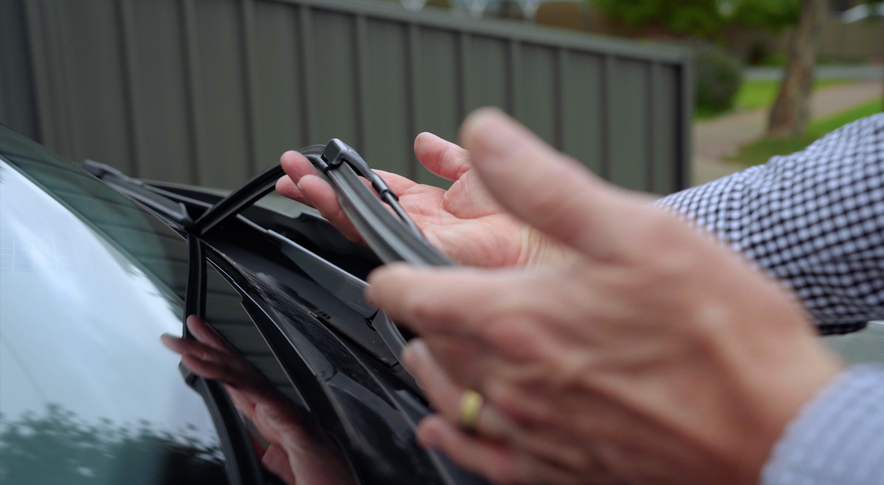 A person checking their windscreen wiper blades.