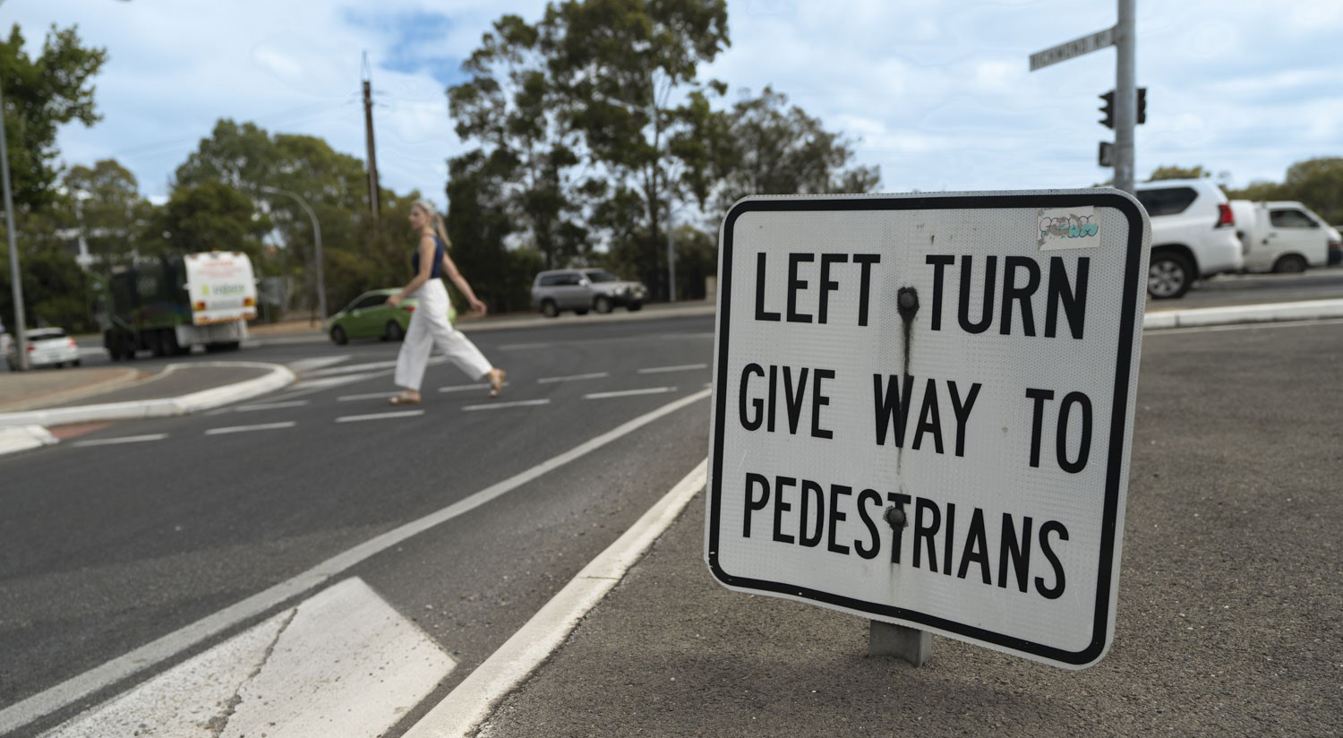 Woman crossing a slip lane on a busy road.