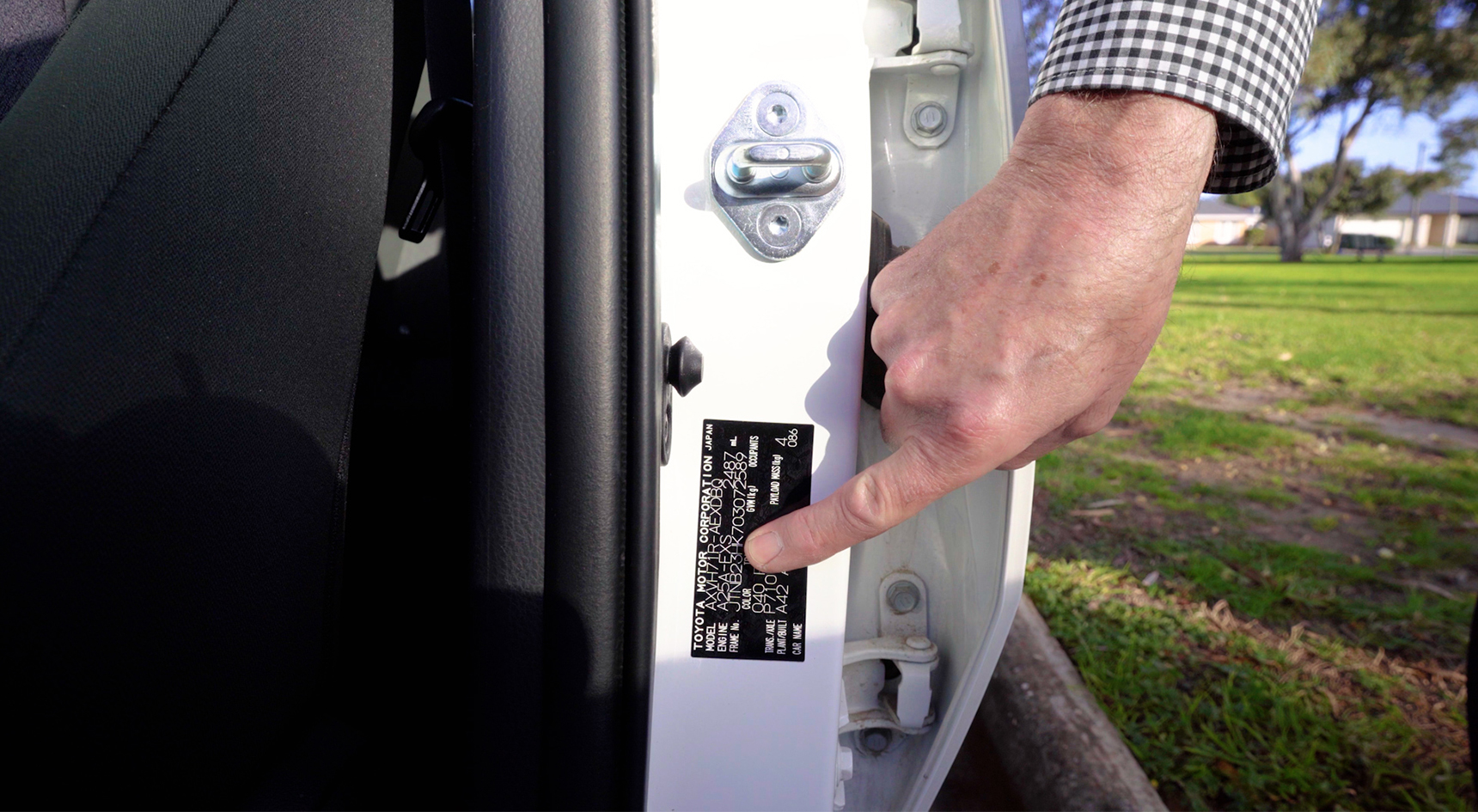 Man pointing to a vehicle's VIN on the compliance plate