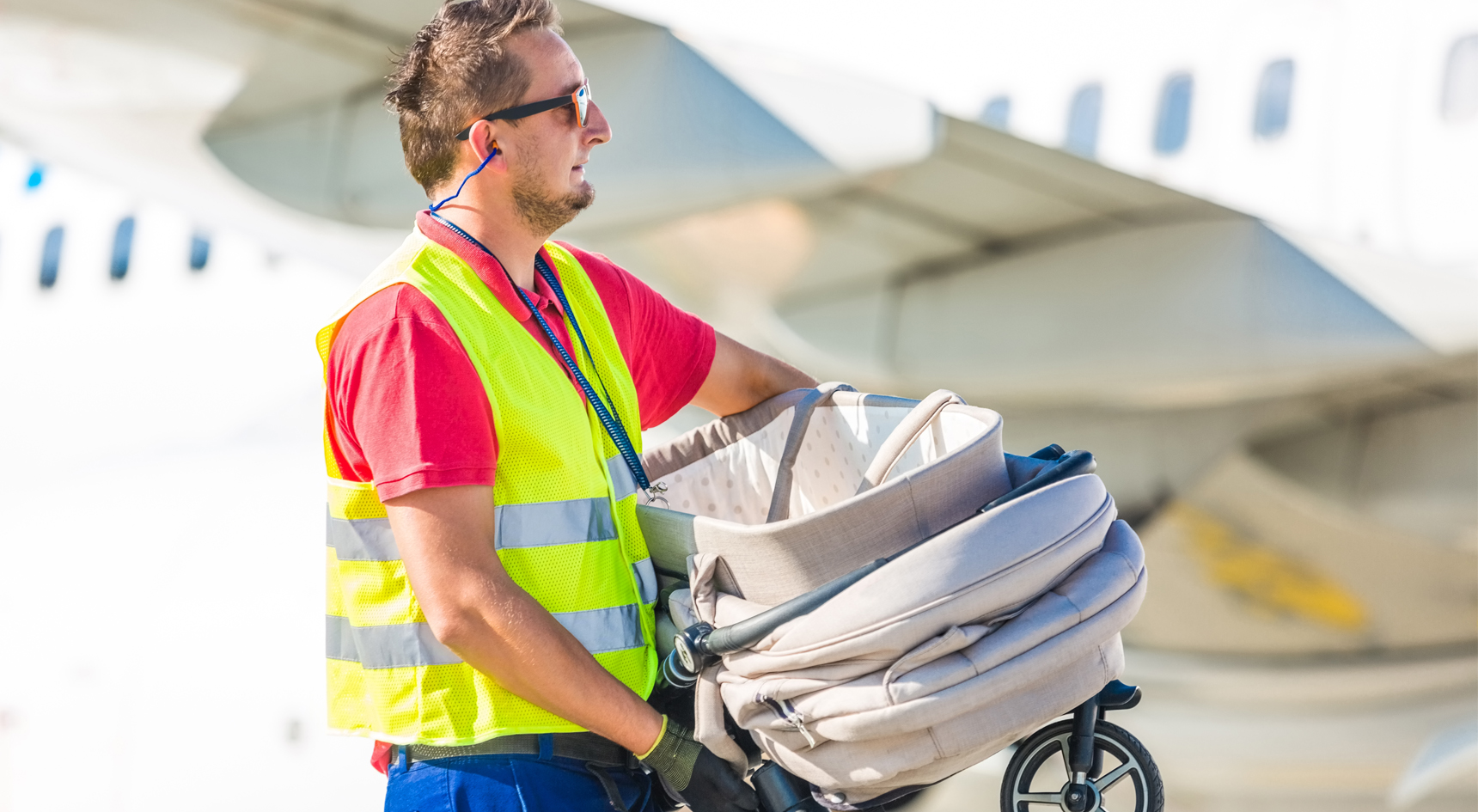Baggage handler carrying a pram.