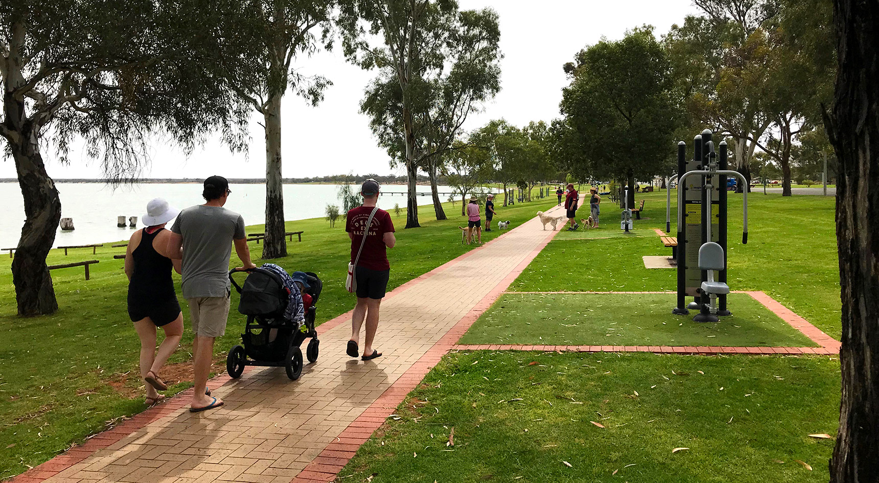 Family pushing a pram alongside a lake