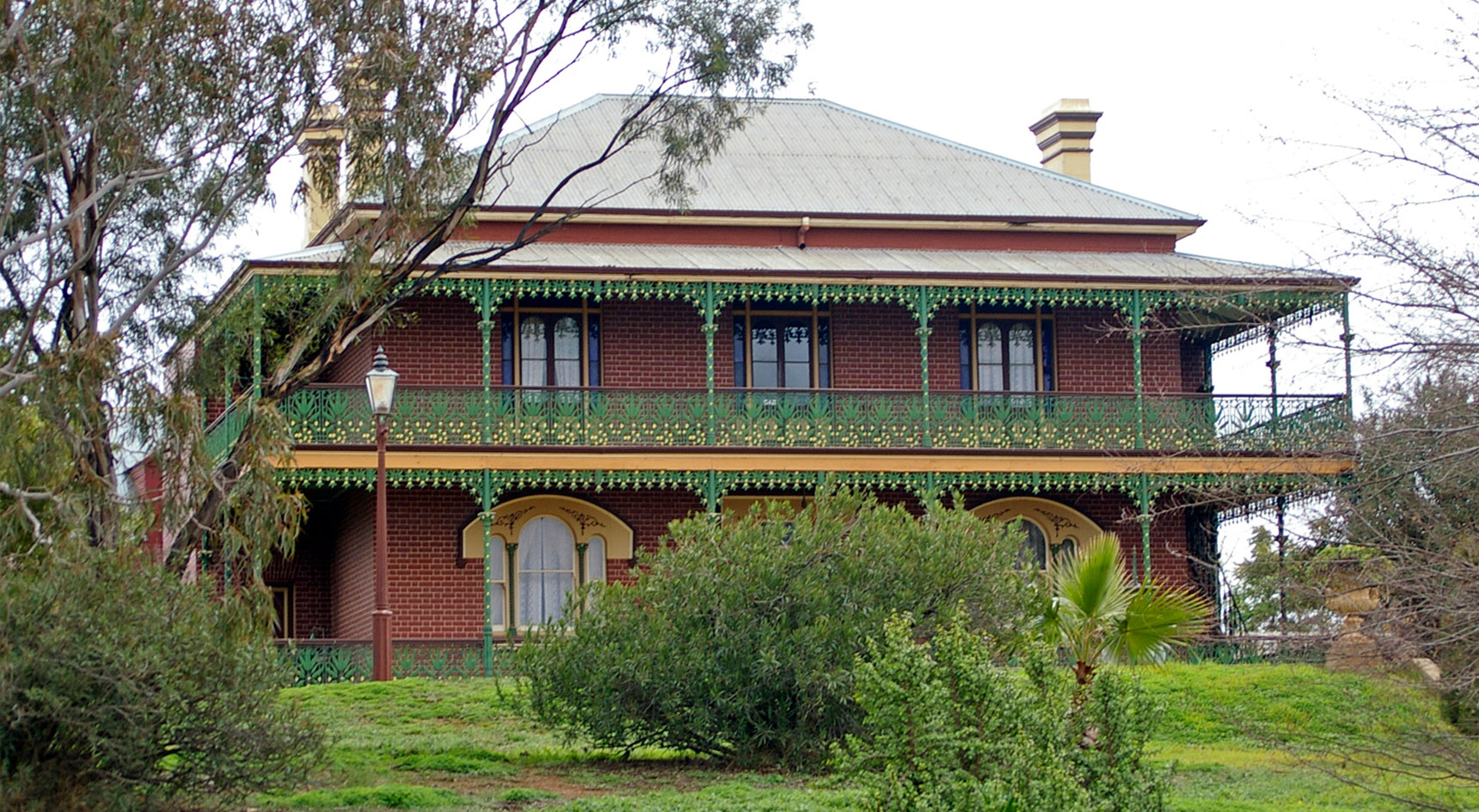 Innocent looking double story red bring terraced house surrounded by trees.