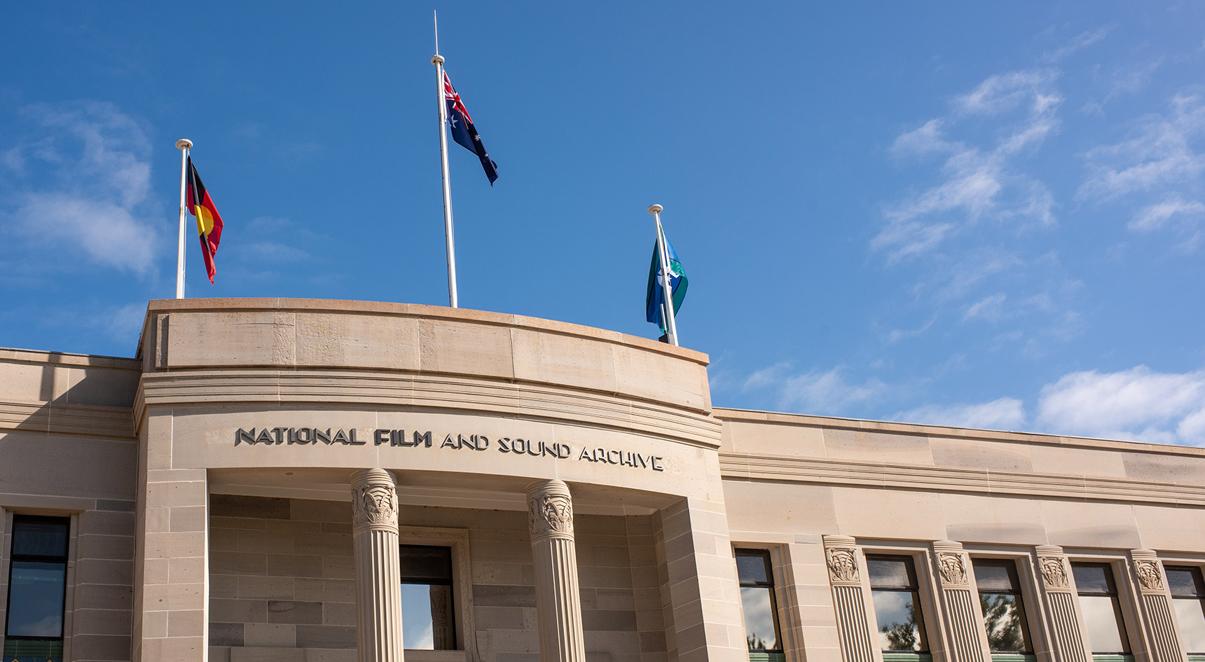Top of a building with the Australian, Aboriginal and Torres Straight Islanders flags. Building name National Film and Sound Archive