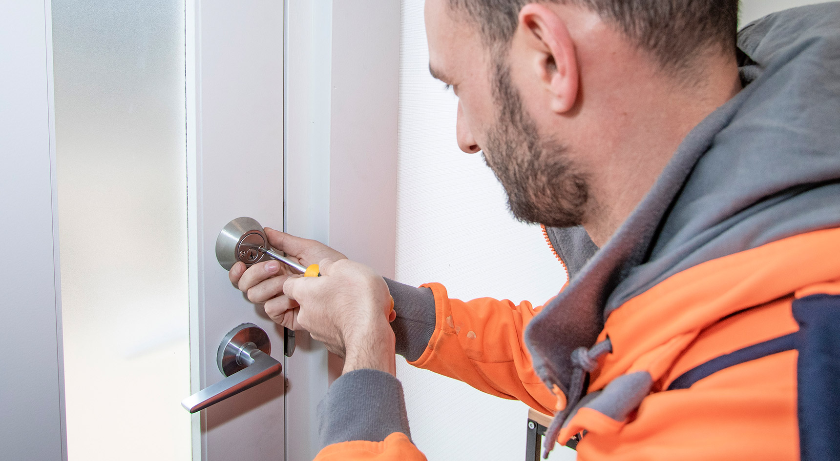 Man affixing a new lock to a door
