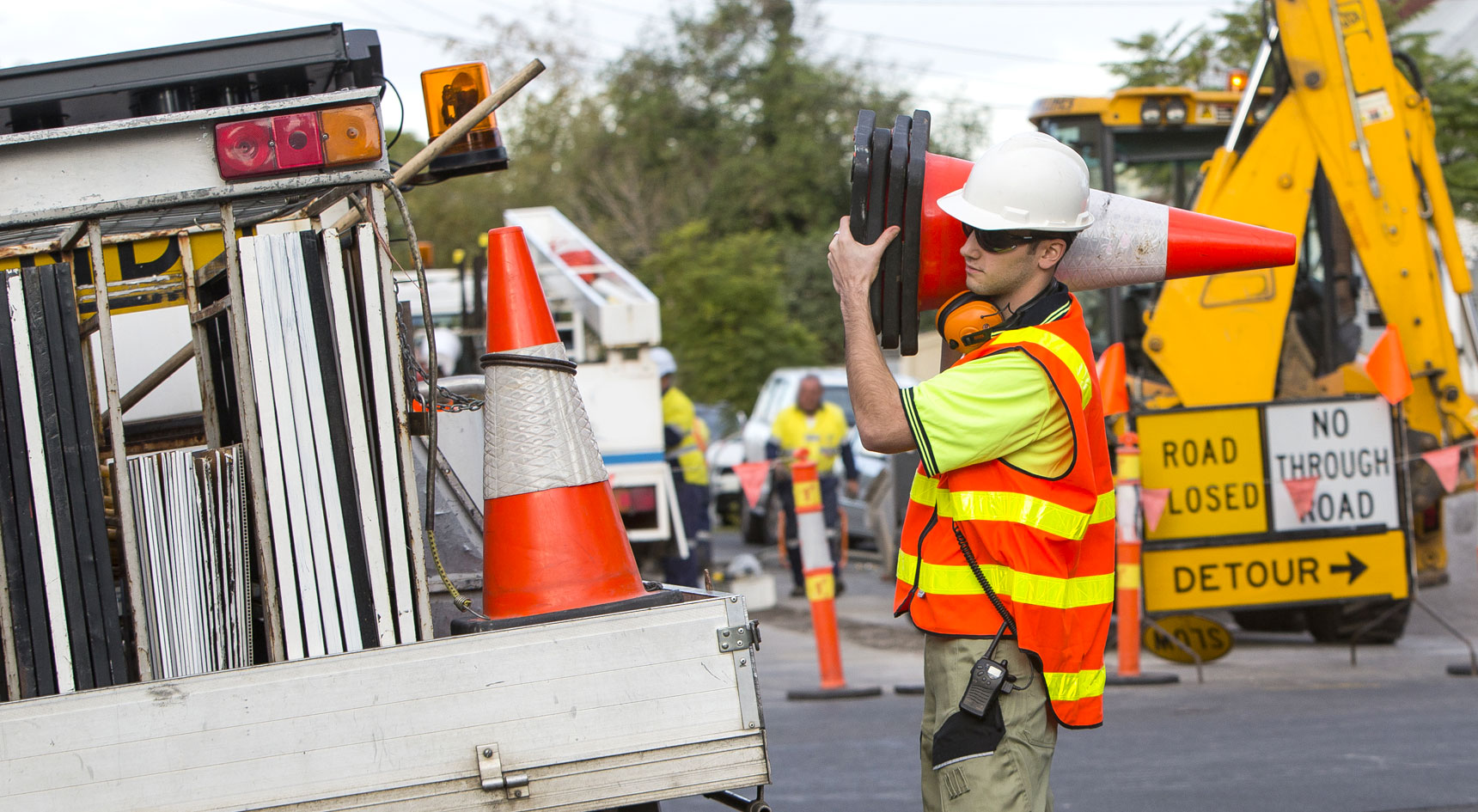 Man holding a traffic cone wearing high vis on a road.
