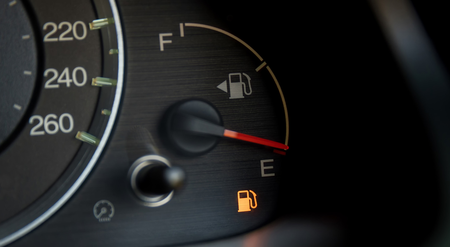 A fuel gauge with the fuel light on.