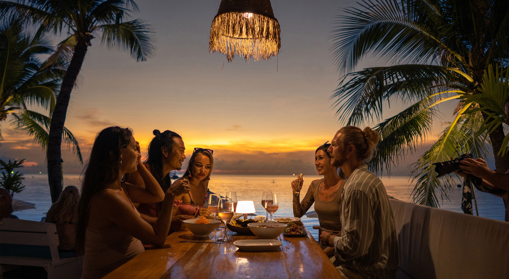 Friends dining on a beach at sunset